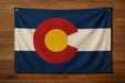 Realistic Colorado flag with brass grommets in all 4 corners mounted to a wood wall