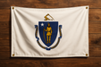 Realistic looking Massachusetts flag with a brass grommet in each corner mounted to a wood wall